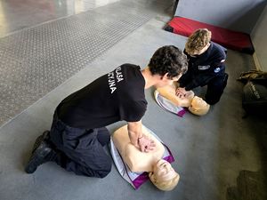 na zdjęciu dwóch uczniów klęczących przy manekinach, wykonują uciski na klatce piersiowej manekinów