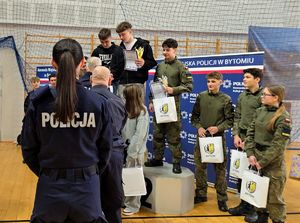 na zdjęciu mundurowi wręczający nagrody uczniom stojącym na podium