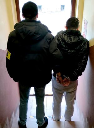 na zdjęciu zatrzymany w kajdankach, obok nieumundurowany policjant trzyma go za ramię