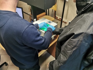 na zdjęciu nieumundurowany policjant w trakcie pobierania śladów daktyloskopijnych zatrzymanego