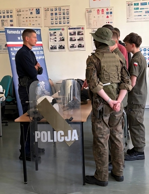 na zdjęciu stoisko policyjne przy nim policjant i uczniowie