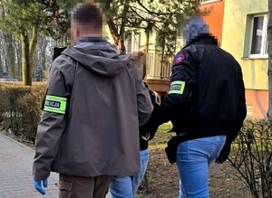 dwóch nieumundurowanych funkcjonariuszy prowadzi zatrzymaną kobietę