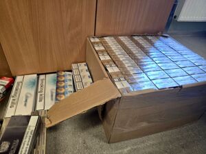 leżący na podłodze karton z paczkami papierosów obok wagony papierosów