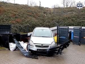 samochód osobowy srebrnego koloru, przy skarpie, przed nim uszkodzone przęsło ogrodzenia