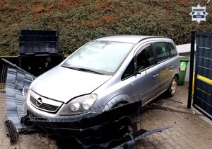 samochód osobowy srebrnego koloru, przy skarpie, przed nim uszkodzone przęsło ogrodzenia