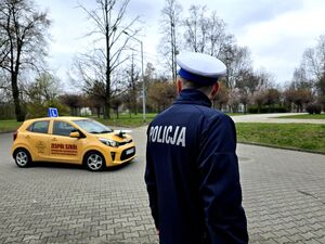 policjant drogówki przy samochodzie do jazdy egzaminacyjnej