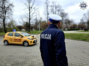 policjant drogówki przy samochodzie do jazdy egzaminacyjnej