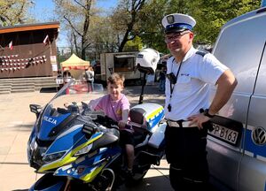 chłopiec na motocyklu służbowym, przy nim policjant ruchu drogowego