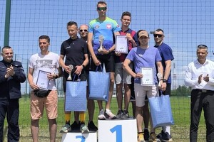 trzy drużyny stojących na podium biegaczy obok mundurowy z drugiej strony prezydent miasta Bytomia