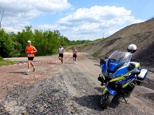 uczestnicy w trakcie biegu obok motocykl policyjny