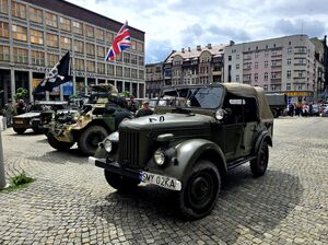 zaparkowane pojazdy militarne i zgromadzone osoby