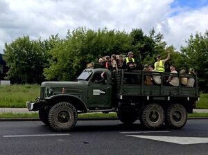 pojazd militarny w nim na dachu kilkanaście osób