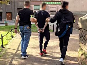 dwóch nieumundurowanych policjantów prowadzi zatrzymanego mężczyznę