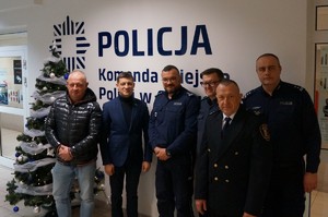 Grupowe zdjęcie uczestników spotkania na tle loga Policji