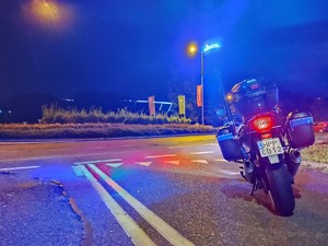 Zdjęcie przedstawia motocykl policyjny z włączonymi światłami uprzywilejowania