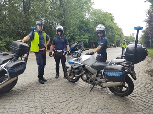 Zdjęcie przedstawia policjantów ruchu drogowego obok motocykli służbowych