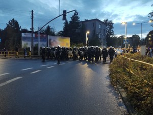 Zdjęcie przedstawia policjantów prowadzących przemarsz kibiców