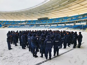 Zdjęcie przedstawia policjantów biorących udział w ćwiczeniach na płycie stadionu