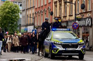 Na zdjęciu radiowóz, za nim dwaj policjanci na koniach i ludzie uczestniczący w przemarszu