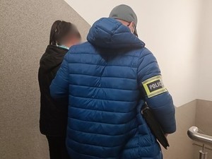 Na zdjęciu policjant obrócony tyłem z zatrzymaną