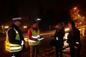 policjanci razem z Adamem Małyszem wręczają elementy odblaskowe pieszym