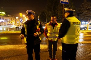 policjanci razem z Adamem Małyszem wręczają elementy odblaskowe pieszym