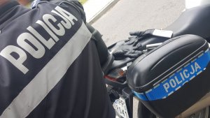 zdjęcie-dzień, widoczny policyjny motocykl i plecy policjanta-napis policja na motocyklu i kurtce policjanta