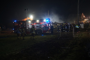 grafika-noc, akcja ratownicza, strażacy pożarni, w tle zniszczony dom, dym unosi się nad domem