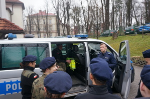 zdjęcie- policjant pokazuje młodzieży z klasy mundurowej radiowóz