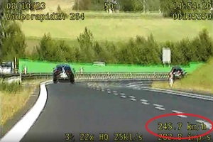 zdjęcie prezentujące kadr z wideorejstratora- dzień, widoczny czarny samochód, zakreślona na czerwono prędkość pojazdu 245 kilometrów na godzinę