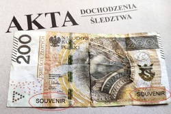 zdjęcie-falsyfikat banknotu na teczce akt postępowania, napis akta dochodzenia