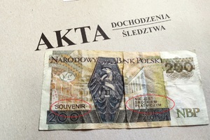 zdjęcie-falsyfikat banknotu na teczce akt postępowania, napis akta dochodzenia