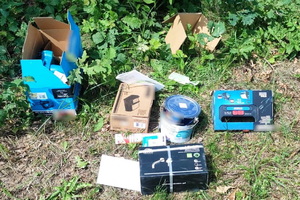 zdjęcie kradzionych przedmiotów na trawniku- piła, farba i inne przedmioty budowlane