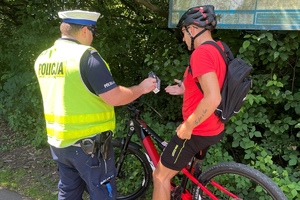 policjant kontroluje rowerzystę, wręcza mu lampki rowerowe, dzień ,słonecznie