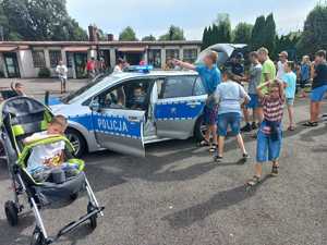 zdjęcie- dzień, plac , policyjny radiowóz, dzieci i policjanci