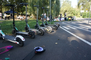 zdjęcie- dzień, słonecznie, hulajnogi na drodze, w tle park