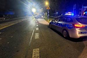 zdjęcie- noc, droga, uszkodzone auto. policyjny radiowóz na sygnale, policjant