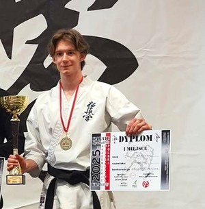 Szymon Bloch z dyplomem i pucharem, ubrany w karate-gi