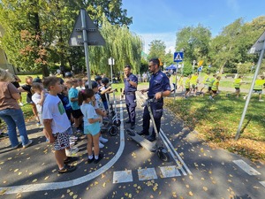 słonecznie, park, policjanci uczą dzieci jeździć na hulajnogach