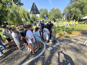 słonecznie, park, policjanci uczą dzieci jeździć na hulajnogach