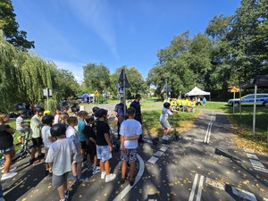 słonecznie, park, policjanci uczą dzieci jeździć na hulajnogach