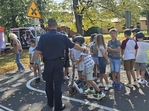słonecznie, park, policjanci uczą dzieci jeździć na hulajnogach