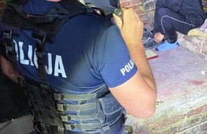 policjant świeci latarka w pomieszczeniu na osobę zatrzymaną