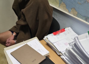 osoba zatrzymana siedzi na krześle, ma kajdanki na dłoniach