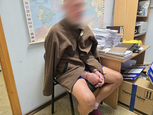 osoba zatrzymana siedzi na krześle, ma kajdanki na dłoniach
