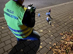 technik kryminalistyki fotografuje przedmiot na chodniku, noc