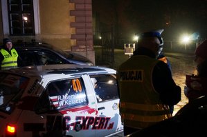 noc, oświetlenie sztuczne, policjant stoi obok samochodu rajdowego