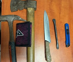 zdjęcie zabezpieczonych niebezpiecznych narzędzi-noże oraz siekiera, ułożone na stole