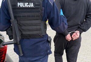 policjant prowadzi osobę zatrzymana, dzień