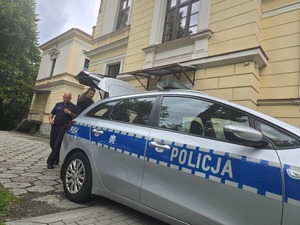 policjanci wnoszą torby do budynku domu dziecka
